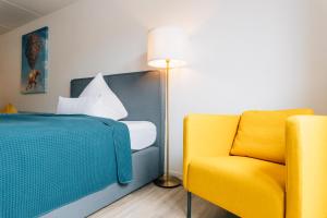 a bedroom with a bed and a yellow chair at Stadt-Appartement am Nordpark in Bielefeld