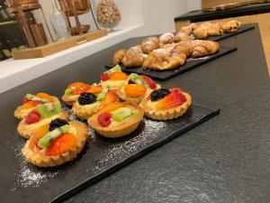 a bunch of fruit tarts on a counter with pastries at Hotel Chalet Alaska in Pozza di Fassa