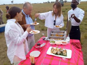 a group of people eating food at a picnic table at Lookout homestay in Sekenani