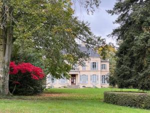 a large house with trees and red flowers in front of it at Demeure des Payratons in Saint-Gérand-le-Puy