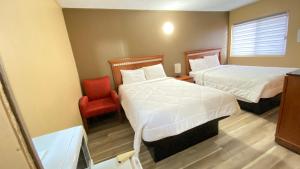 Una habitación de hotel con dos camas y una silla roja. en Rolphton Motel and Restaurant, en Moor Lake Station 1 foto más