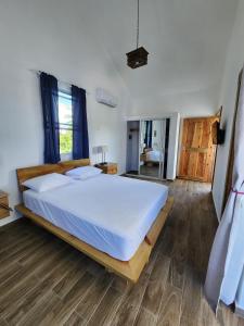 Schlafzimmer mit einem großen weißen Bett und Holzböden in der Unterkunft Room with large pool and close to beach in Las Galeras