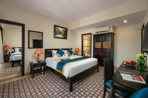 a bedroom with a king sized bed and a desk at La Charm Hoi An Hotel - Peaceful Boutique In Old Town in Hoi An +148 photos