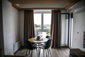 a dining room with a table and chairs and a large window at Lena_Lux in Jagodina