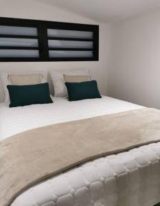 1 cama blanca grande con 2 almohadas verdes en Bienvenue à La Caz'A Loca, en Saint-Pierre