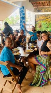 een groep mensen die aan een tafel zitten bij Hostel Recanto da Sereia in Salvador