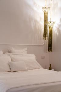 a white bed with white sheets and gold chandeliers at Nest House & Relax in Civitanova Marche