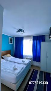a bedroom with a large bed with blue curtains at Eden Apartament in Reghin