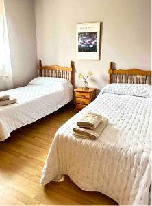 a bedroom with two beds and a wooden floor at Casa Outeiro in Betanzos