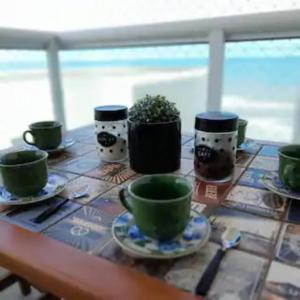 un tavolo con tazze verdi e piattini sopra di Apartamento Vista Mar Mongaguá a Mongaguá
