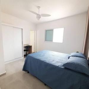 a bedroom with a blue bed and a ceiling fan at Apartamento Vista Mar Mongaguá in Mongaguá