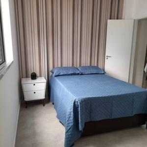 um quarto com uma cama azul e uma mesa de cabeceira em Apartamento Vista Mar Mongaguá em Mongaguá