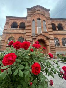 un grupo de rosas rojas frente a un edificio en Najaryan's Family Guest House en Vagharshapat