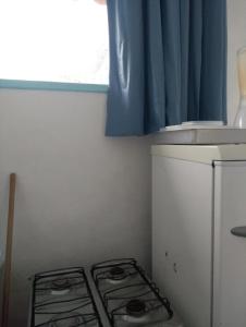 a kitchen with a stove and a blue curtain at Antonia Hospedaria 4 in Búzios
