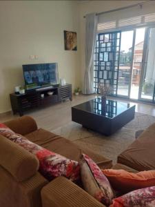 un soggiorno con divano e TV di Beautiful 2-Bed Apartment in Akright City Bwebajja a Namulanda
