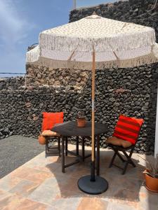 a table and two chairs with an umbrella at Casa Cabrera - 2 apartamentos con vistas al mar in Caleta de Caballo