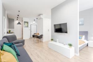 ein Wohnzimmer mit einem Sofa und einem TV an der Wand in der Unterkunft Warsaw City Apartments EXPO in Warschau