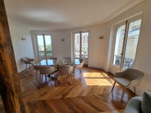 uma sala de jantar com mesa, cadeiras e janelas em Face château St Germain en Laye, appartement 4 à 6 personnes, 23 min de Paris Champs-Elysées em Saint-Germain-en-Laye