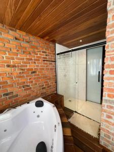 a bath tub in a room with a brick wall at Casa da Pedra Serrinha in Resende