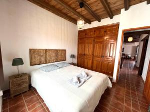 a bedroom with a large white bed with wooden cabinets at Casa del Burro Perezoso in Almáchar +28 photos