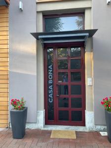 une porte rouge sur un bâtiment avec deux plantes en pot dans l'établissement B&B Casa Bona, à Alba