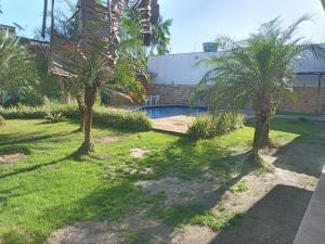 un patio con 2 palmeras y una piscina en Pousada das Acácias, en Carananduba