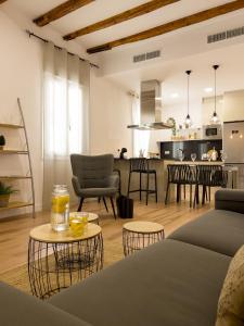 a living room with a couch and tables and a kitchen at Somos Genius! Siéntete como en casa, en el corazón de Tarragona in Tarragona