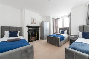 a bedroom with two beds and a fireplace at Lovely 5 Bed house in Medway sleeps 12 in Gillingham