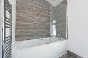 a bathroom with a tub and a mirror at Lovely 5 Bed house in Medway sleeps 12 in Gillingham