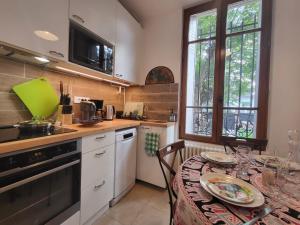 eine Küche mit einem Esstisch und eine Küche mit einer Spüle in der Unterkunft La Violeta - agréable maison jardin RER B - Metro 4 in Arcueil