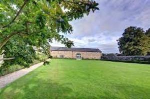 a large green field with a building in the background at The Coach House, Wrexham Road in Wrexham