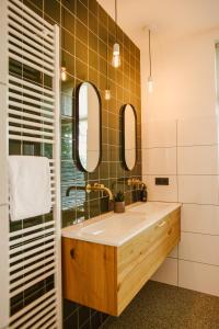 ein Bad mit einem Waschbecken und 2 Spiegeln in der Unterkunft Boutiquehotel & Tiny houses PLEK17 in Milsbeek