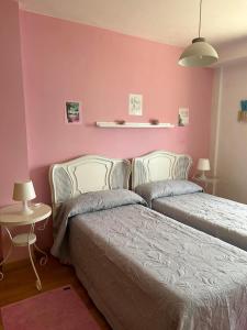 1 Schlafzimmer mit 2 Betten und einer rosa Wand in der Unterkunft Casa Mar de Ardora in Carnota