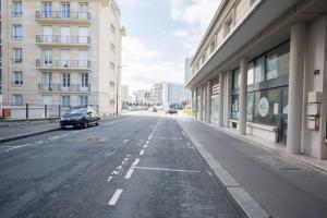 ein Auto, das eine Straße entlang fährt, neben Gebäuden in der Unterkunft L'appar-T, esprit industriel à 2 pas de l'eau ! in Le Havre