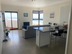 eine Küche und ein Wohnzimmer mit einem Sofa und einem Tisch in der Unterkunft Appartement avec vue imprenable sur l'océan in Praia da Areia Branca