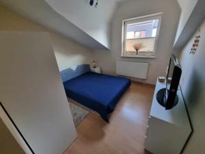 Un pequeño dormitorio con una cama azul y una ventana en Apartament Mewa Gdańsk, en Gdansk