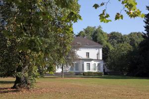 een wit huis met een boom op de voorgrond bij Apartment Düsseldorf-Lohausen in Düsseldorf