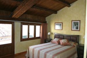 Un dormitorio con una cama y dos ventanas. en Casa rural Daudén, en Cantavieja