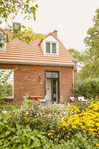 a brick house with a garden of flowers at Boutiquehotel & Tiny houses PLEK17 in Milsbeek
