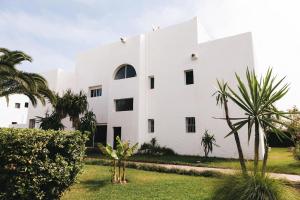 a white building with palm trees in front of it at Villa Vue sur la Méditerranée in Cabo Negro