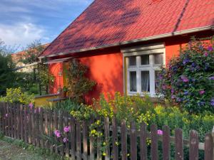 una casa roja con una valla de madera y flores en Villa Kunterbunt: Urgemütlich und fast perfekt, en Hohen Wangelin