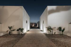 a walkway leading into a white building at night at Cove Paros in Naousa