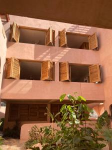 a pink building with wooden shutters on it at Casa Liquen in Chacala