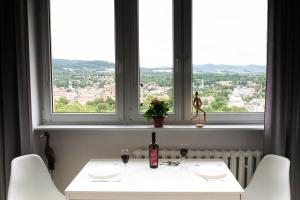 ein Fenster mit einem weißen Tisch und einer Flasche Wein in der Unterkunft Na chmury i góry - apartament in Kłodzko