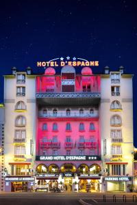 un bâtiment avec un panneau néon à l'avant de celui-ci dans l'établissement Grand Hôtel d'Espagne, à Lourdes