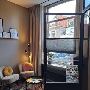 a room with a window and a chair and a table at Bij Ons In Harlingen in Harlingen