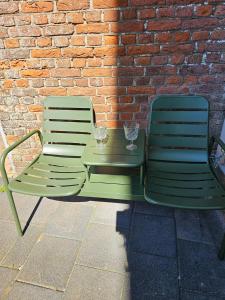 two green chairs and a table in front of a brick wall at Bij Ons In Harlingen in Harlingen
