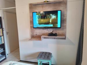TV de pantalla plana en la pared con taburete en Apt com vista para o mar, en Capão da Canoa