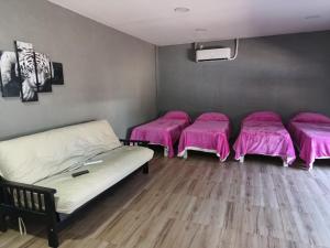 Habitación con 3 camas y mantas rosas. en Residencia Dos Soles 2.0 en Resistencia