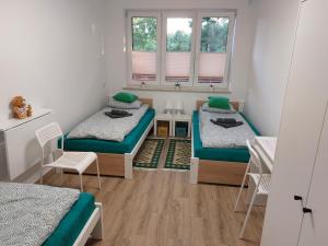 a room with two beds and a table and two windows at Apartament Zagórze, bezpłatny ogrodzony parking, Netflix in Kielce